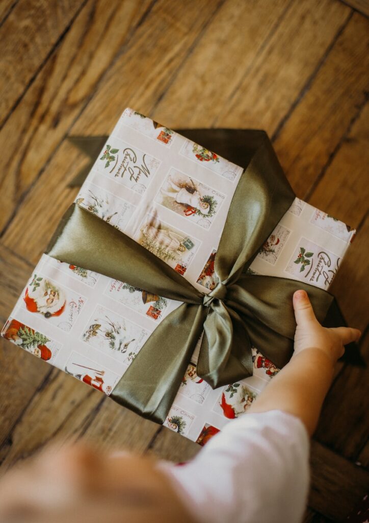 a person holding a wrapped present on a wooden floor